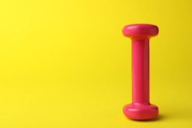 Photo of Stylish dumbbell on yellow background, space for text