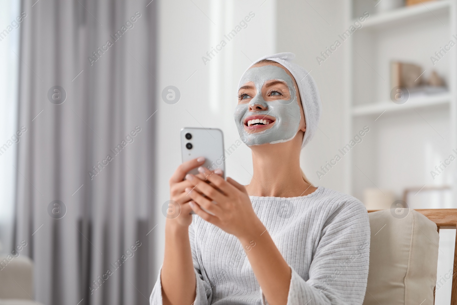 Photo of Young woman with face mask using smartphone at home, space for text. Spa treatments