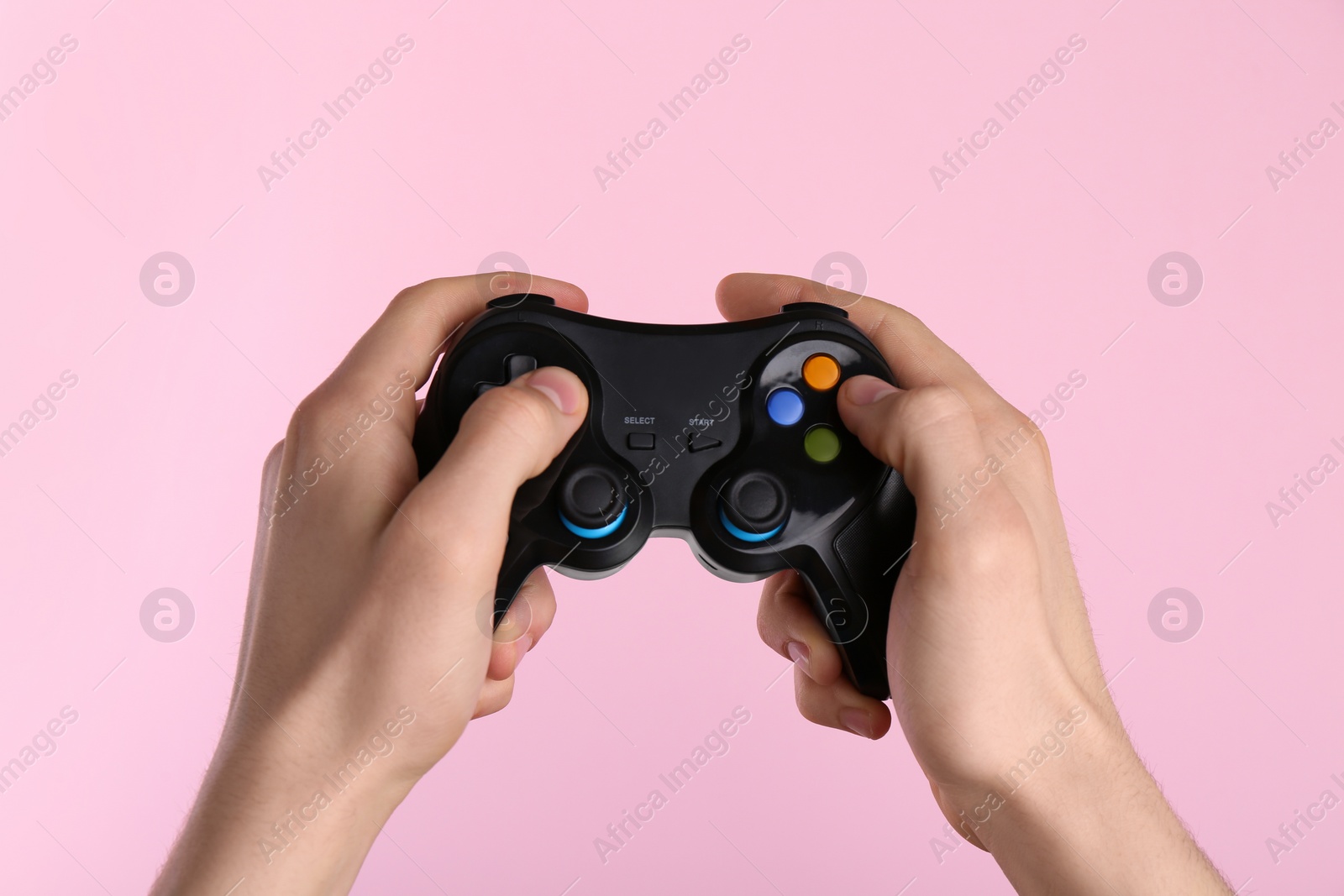 Photo of Man using wireless game controller on pink background, closeup