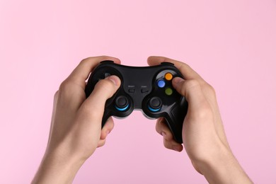 Photo of Man using wireless game controller on pink background, closeup