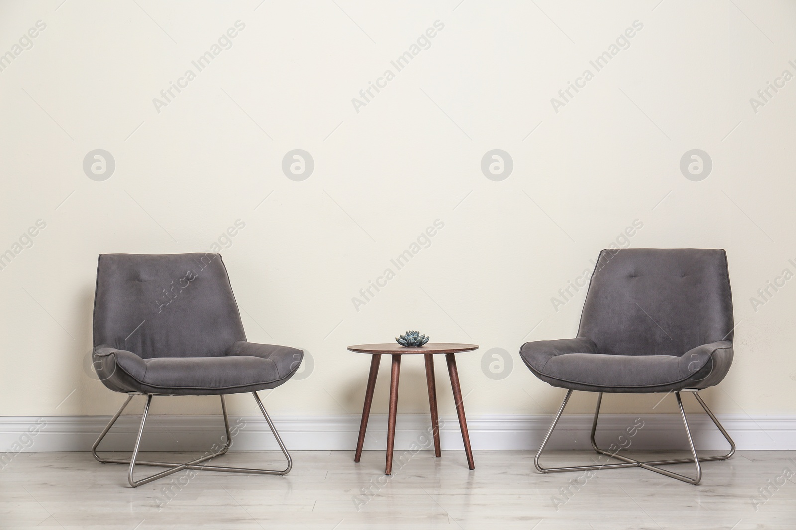 Photo of Room interior with modern chairs and table near light wall