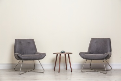 Photo of Room interior with modern chairs and table near light wall