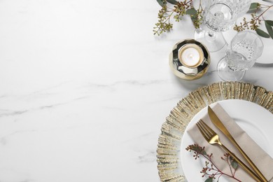 Photo of Stylish setting with cutlery, burning candle and eucalyptus leaves on white marble table, flat lay. Space for text