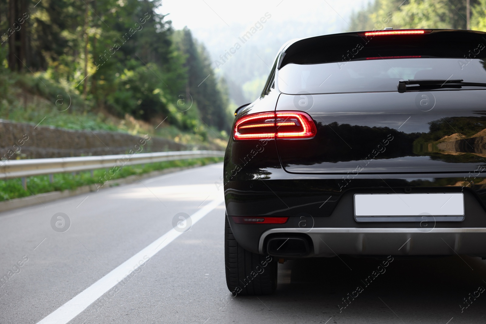 Photo of Modern black car on asphalt road outdoors, space for text