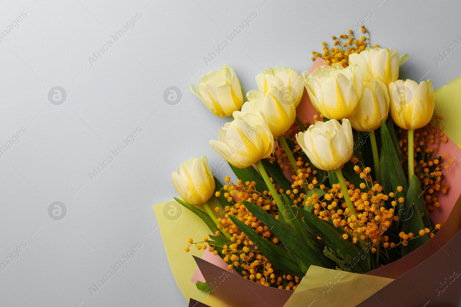 Photo of Bouquet with beautiful tulips and mimosa flowers on light grey background, top view. Space for text