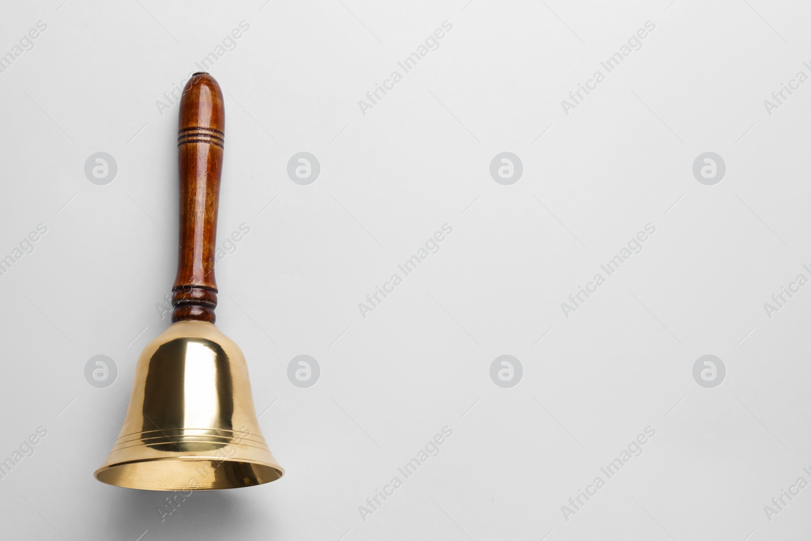 Photo of Golden school bell with wooden handle on grey background, top view. Space for text