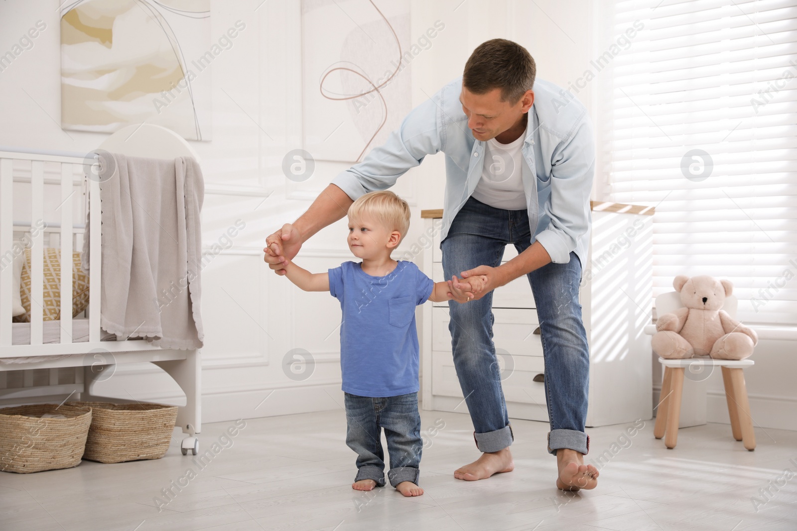 Photo of Little boy walking with father's help in nursery