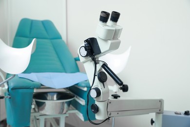 Photo of Modern binocular colposcope and gynecological chair in clinic