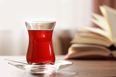 Glass of traditional Turkish tea on wooden table, closeup. Space for text