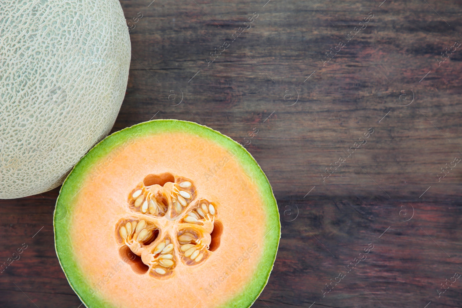 Photo of Whole and cut fresh ripe melons on wooden table, flat lay. Space for text