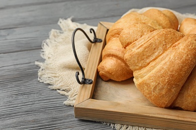 Tray with tasty croissants on wooden table