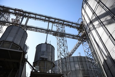 Photo of Modern granaries for storing cereal grains against blue sky, low angle view