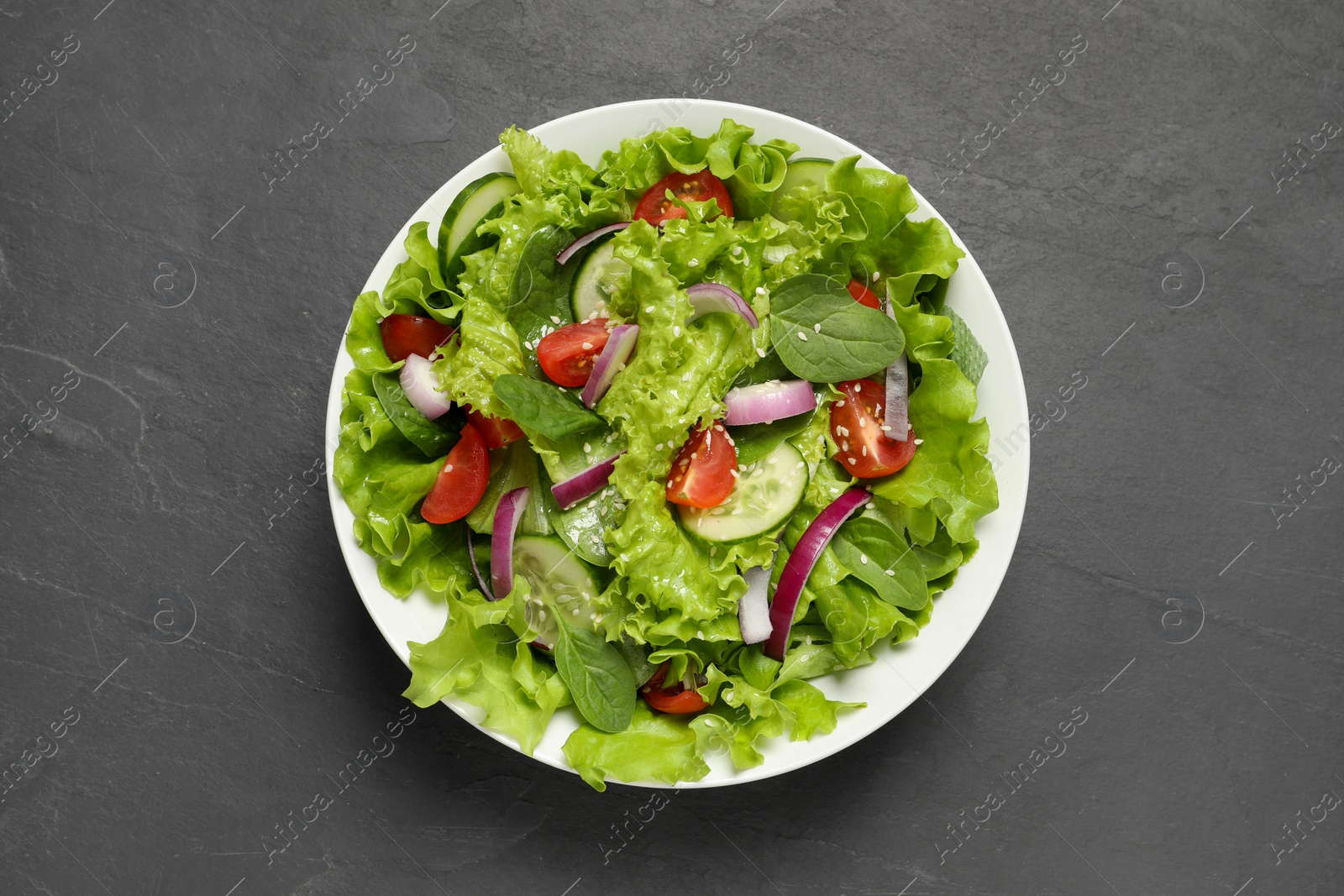 Photo of Delicious salad in bowl on grey table, top view