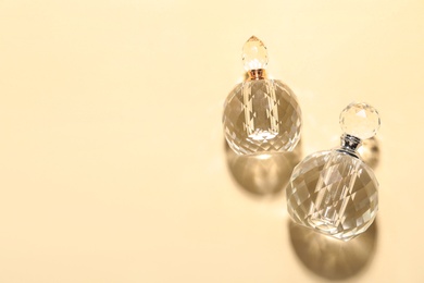 Different elegant perfume bottles on beige background, flat lay. Space for text