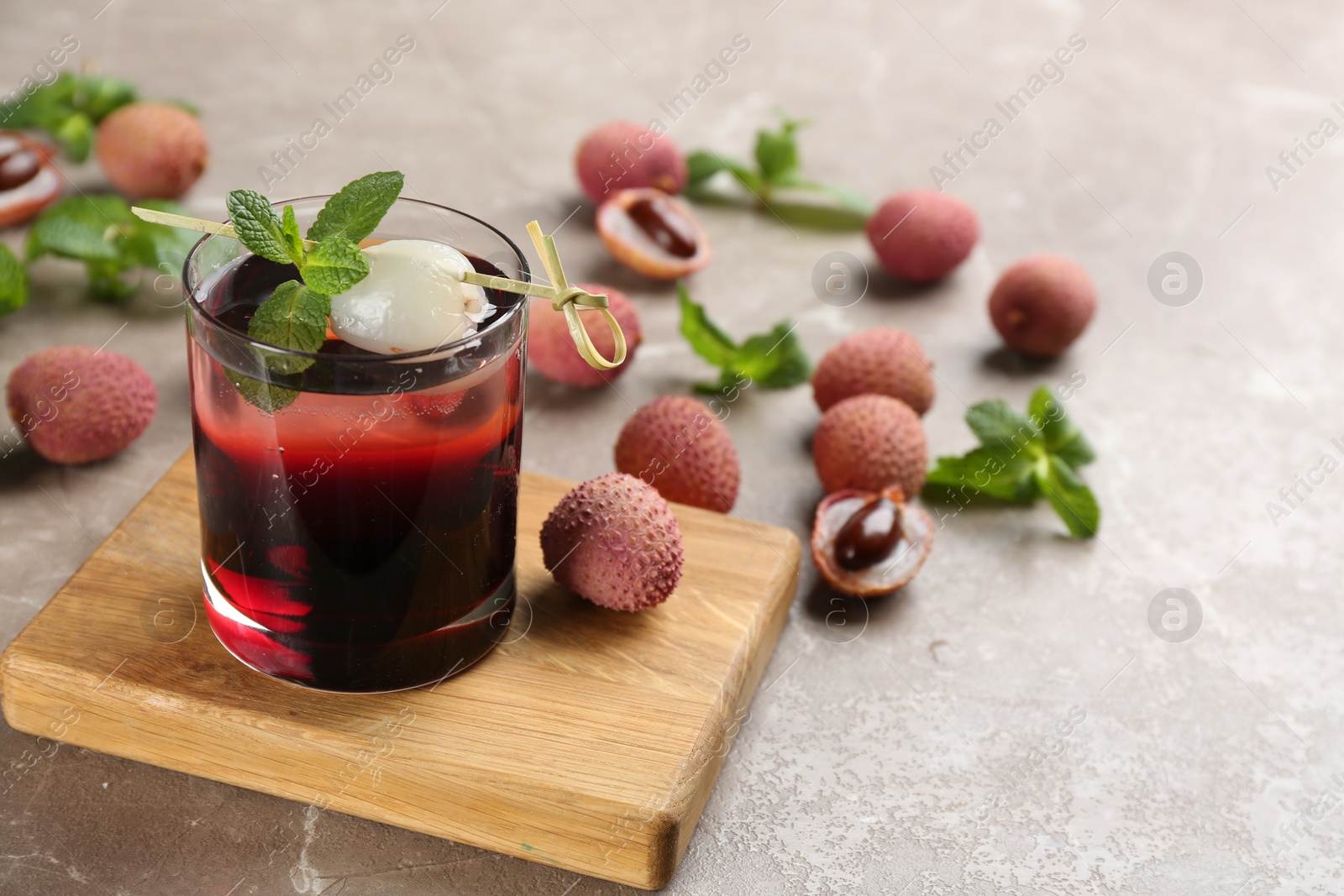 Photo of Lychee cocktail with mint and fresh fruits on grey table, space for text