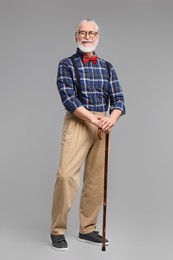 Senior man with walking cane on gray background