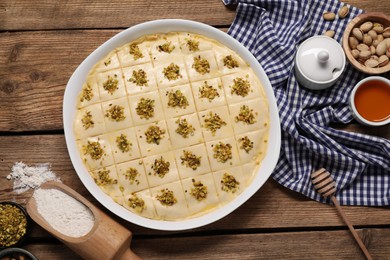 Photo of Making delicious baklava. Raw dough with ingredients on wooden table, flat lay