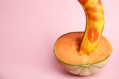 Fresh banana with red lipstick marks and melon on pink background, space for text. Sex concept