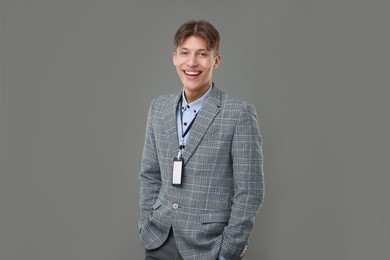 Happy man with blank badge on grey background