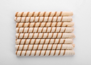 Tasty wafer roll sticks on white background, top view. Crispy food