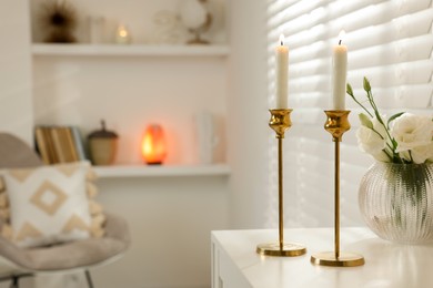 Photo of Pair of beautiful golden candlesticks on white table in room, space for text