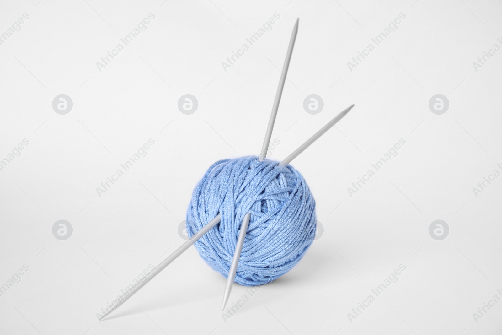 Photo of Soft light blue woolen yarn and knitting needles on white background