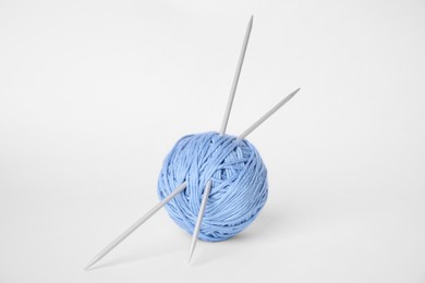 Photo of Soft light blue woolen yarn and knitting needles on white background