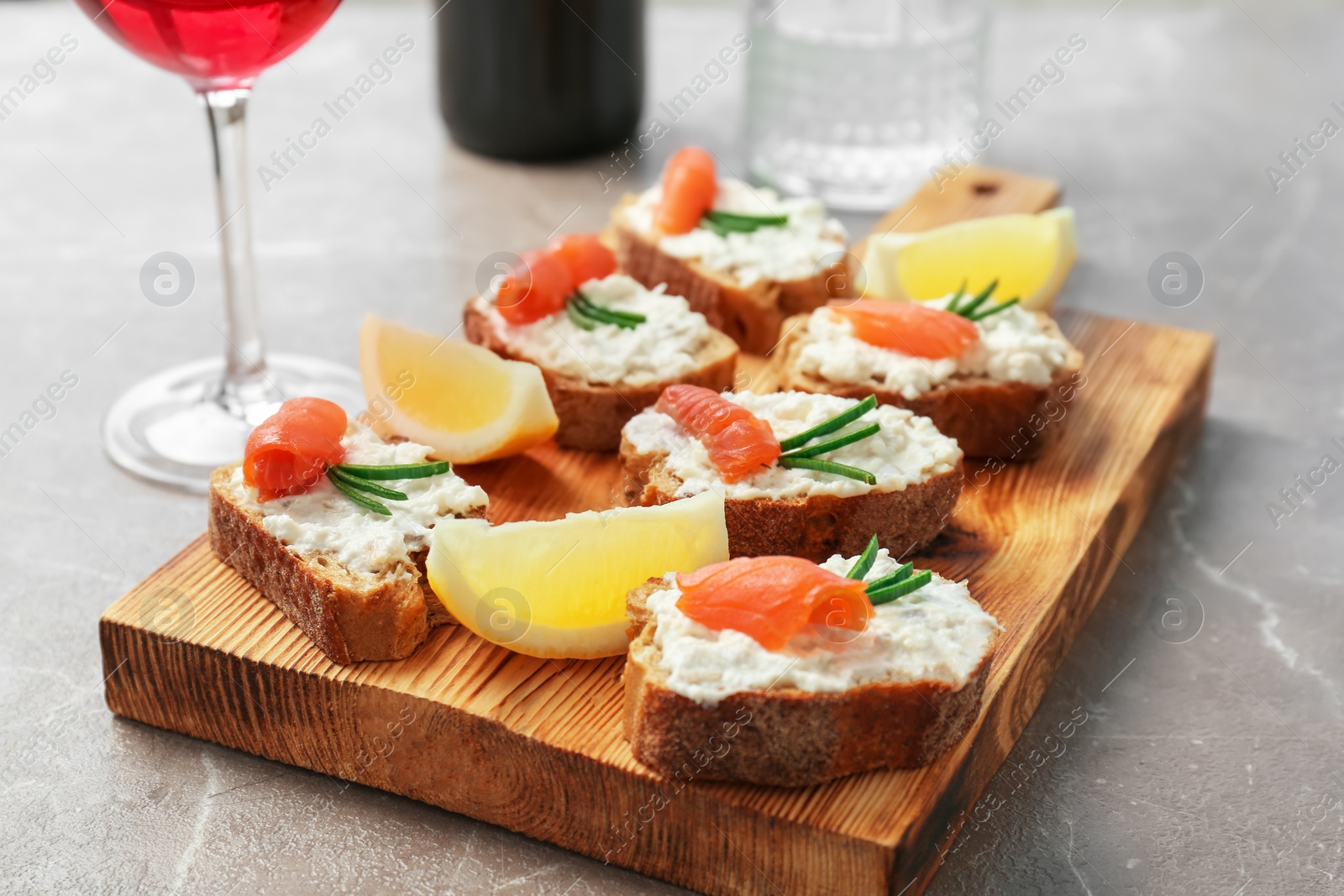 Photo of Sandwiches with fresh sliced salmon fillet on wooden board, closeup