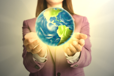 Image of Woman holding Earth on light background, closeup