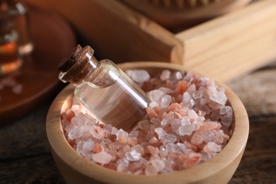 Photo of Spa treatment. Sea salt and bottle of essential oil in bowl on table, closeup