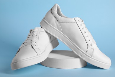 Pair of stylish white sneakers on light blue background