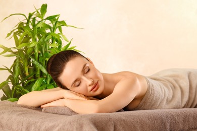 Image of Beautiful young woman relaxing in spa salon. Green bamboo stems on background