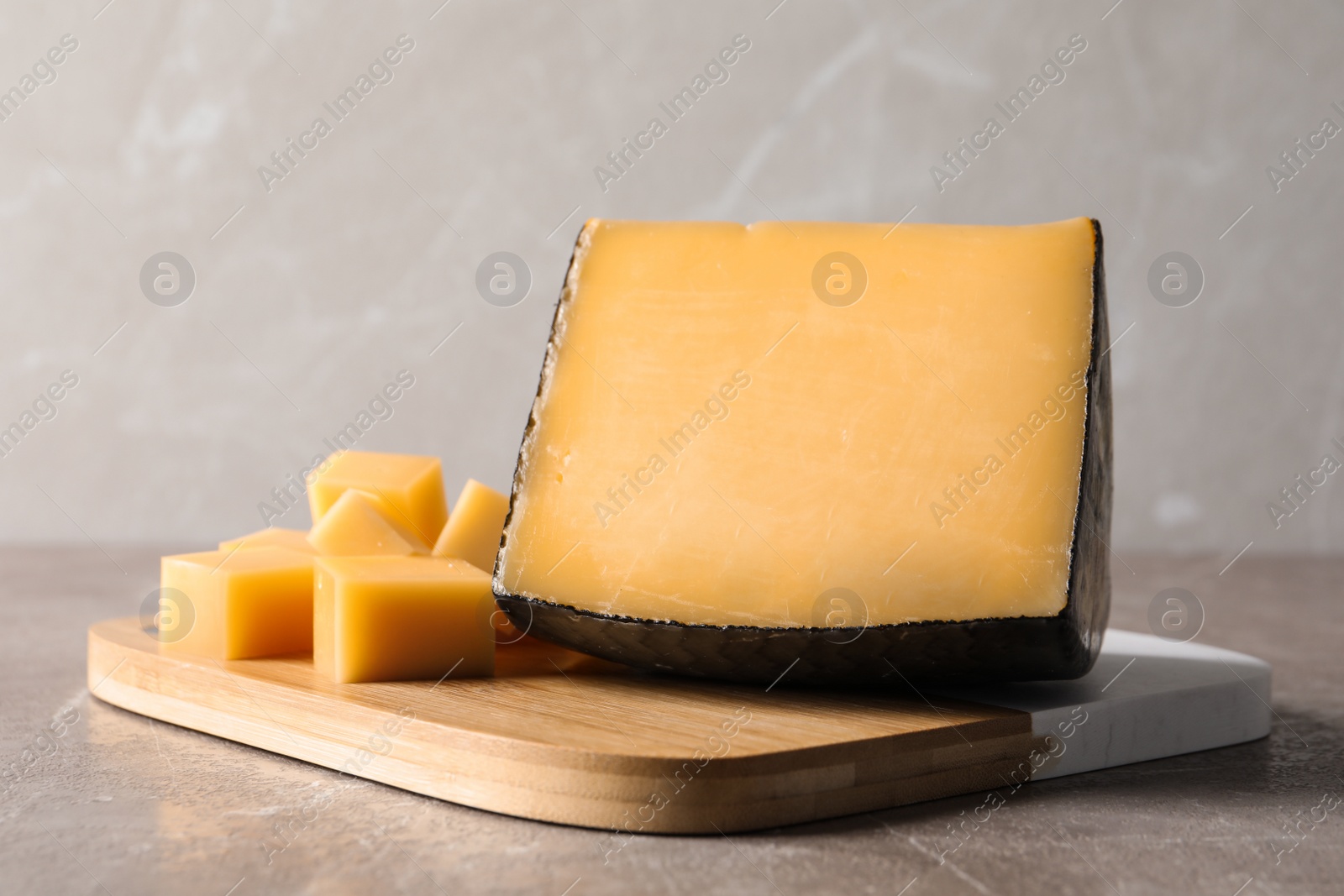 Photo of Board with delicious cut cheese on marble table