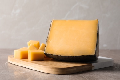 Board with delicious cut cheese on marble table