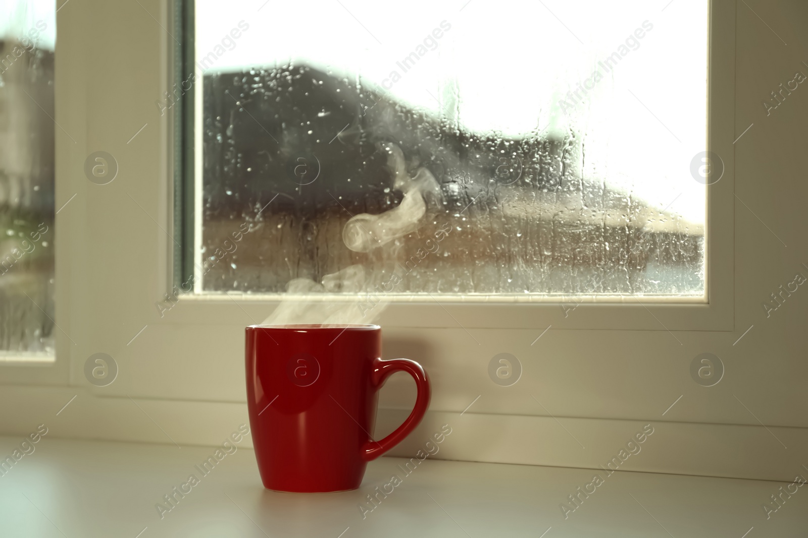 Photo of Cup of hot drink near window on rainy day. Space for text