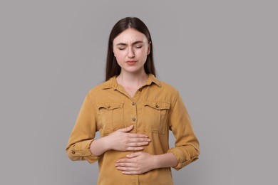 Photo of Young woman suffering from stomach pain on grey background