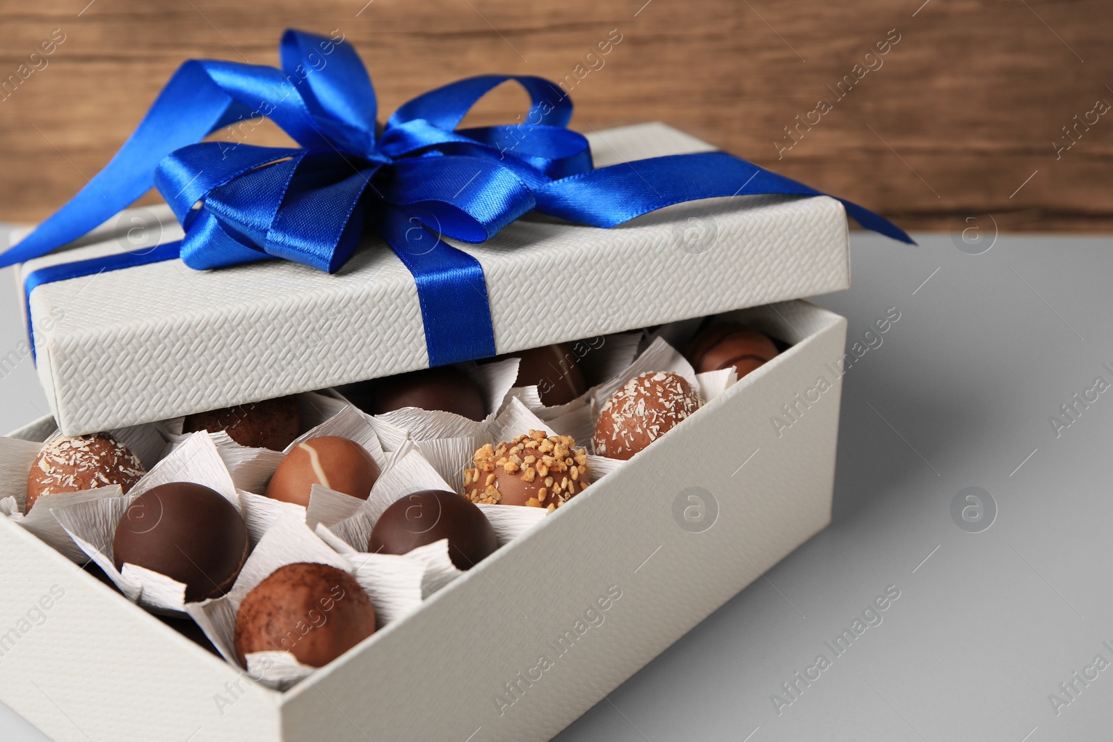 Photo of Box with delicious chocolate candies on beige background, closeup