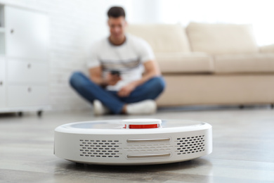 Photo of Man resting while robotic vacuum cleaner doing his work at home