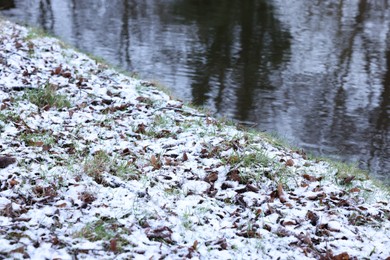 Green grass covered with snow and water canal on winter day