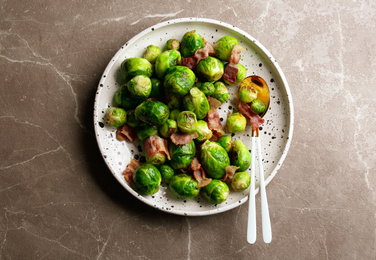 Photo of Delicious Brussels sprouts with bacon on marble table, top view