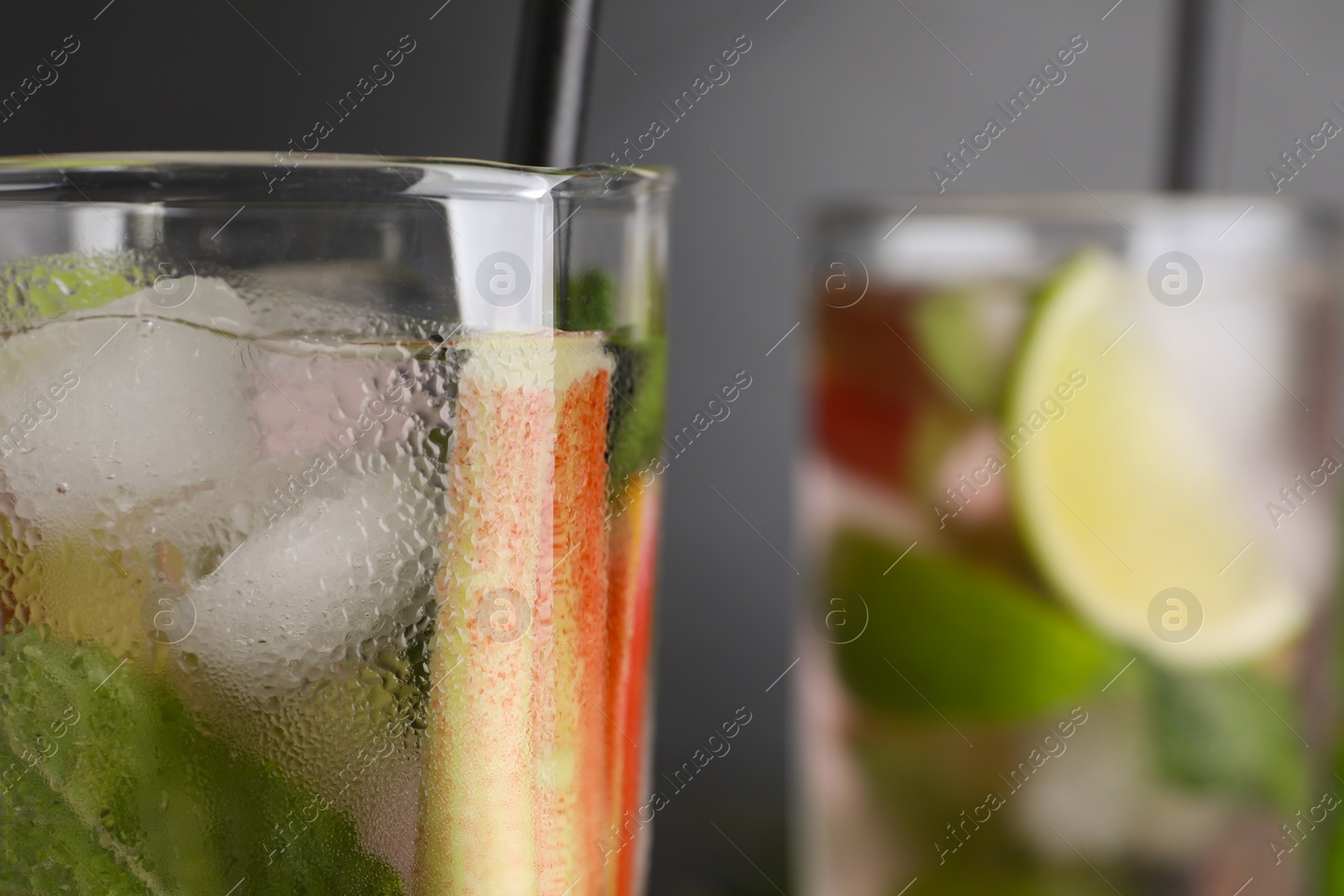Photo of Glass of tasty rhubarb cocktail with lime against blurred background, closeup. Space for text