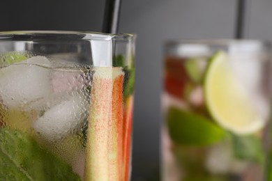 Photo of Glass of tasty rhubarb cocktail with lime against blurred background, closeup. Space for text