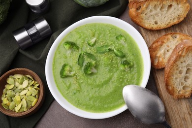 Photo of Delicious broccoli cream soup served on grey table, flat lay
