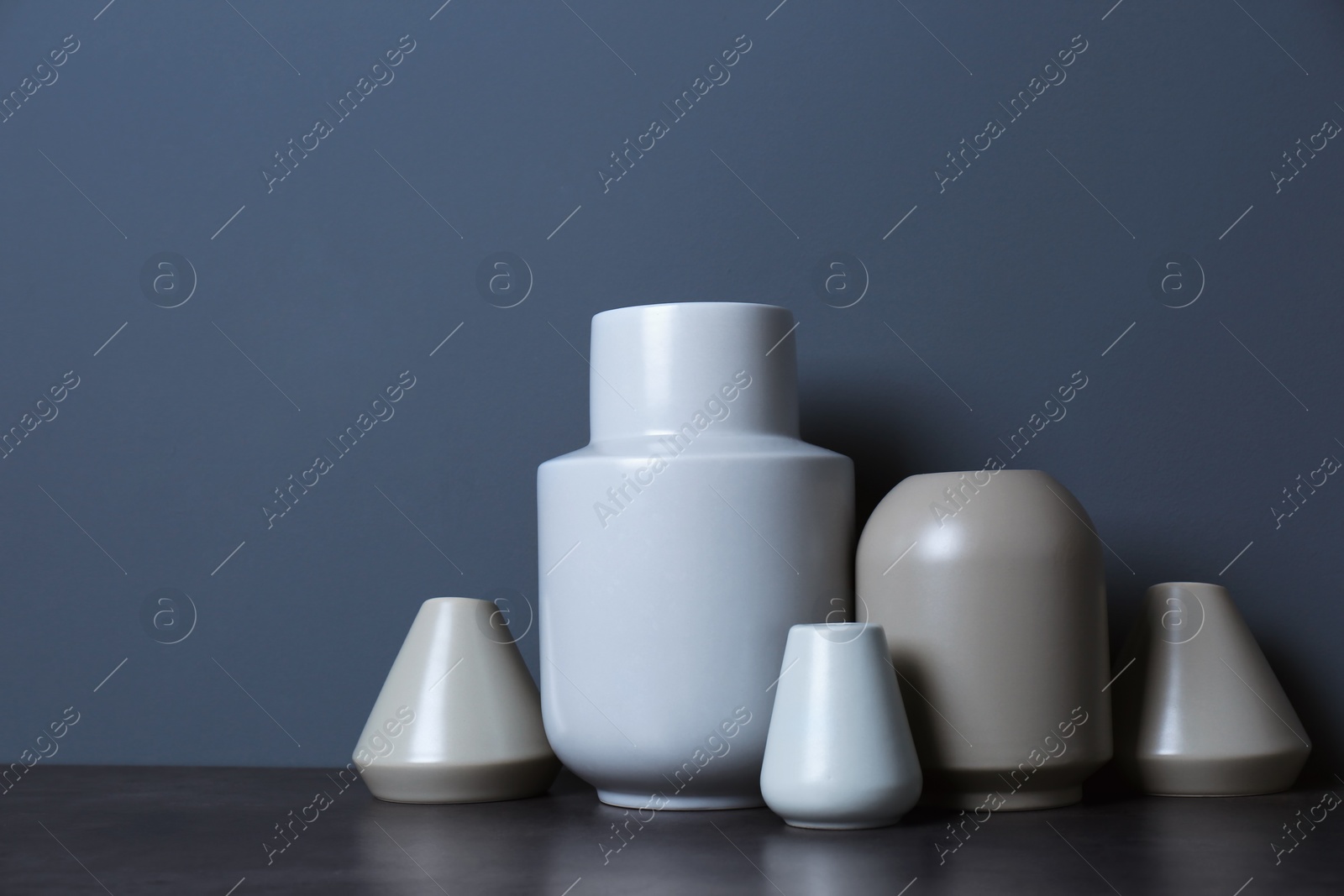 Photo of Beautiful ceramic vases on table against color wall with space for text