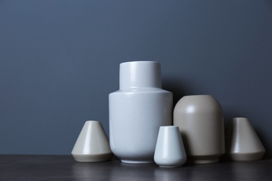 Beautiful ceramic vases on table against color wall with space for text