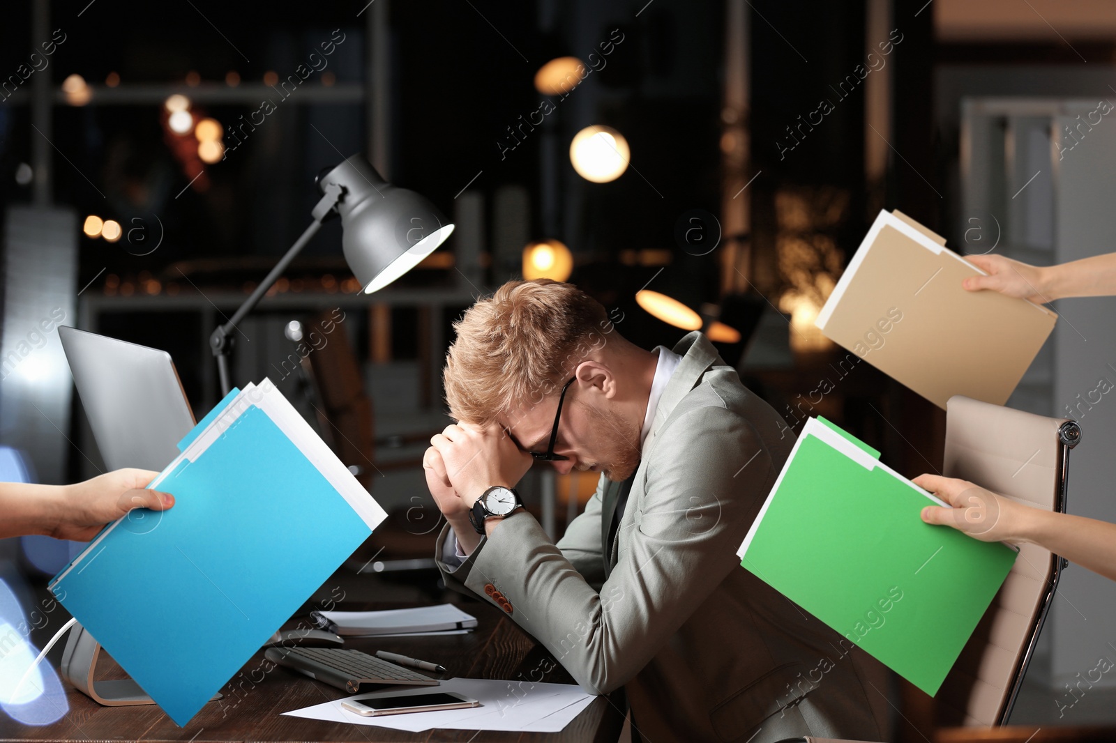 Image of Deadline concept. Colleagues giving folders with documents to overwhelmed man at desk in evening