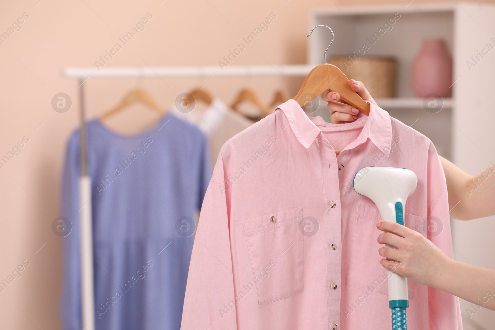 Photo of Woman steaming shirt on hanger at home, closeup. Space for text