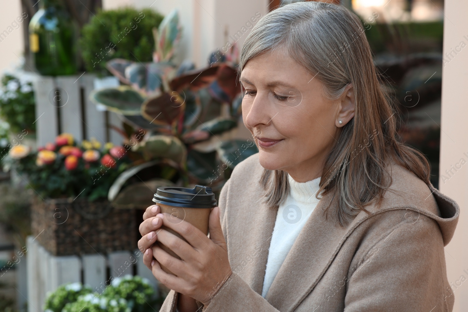 Photo of Beautiful senior woman sitting in outdoor cafe and drinking coffee, space for text