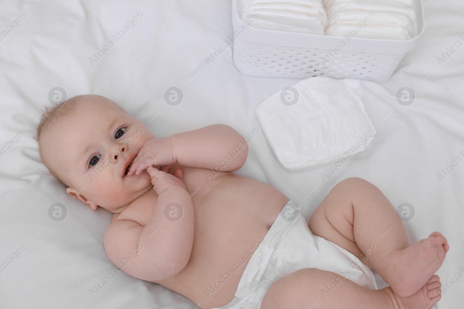 Photo of Cute baby and diapers on white bed
