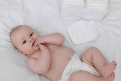 Cute baby and diapers on white bed